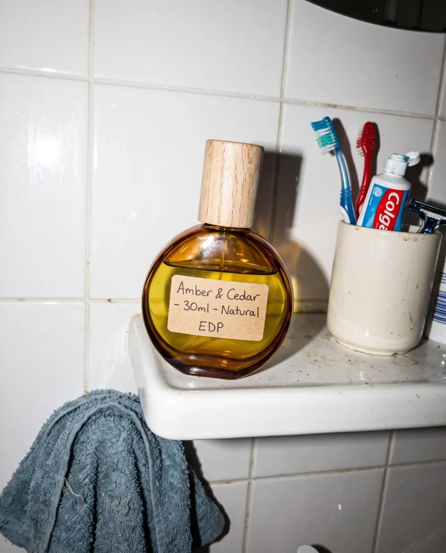 زجاجة عطر كهرمانية مصوّرة بالهاتف على رفّ حمّام