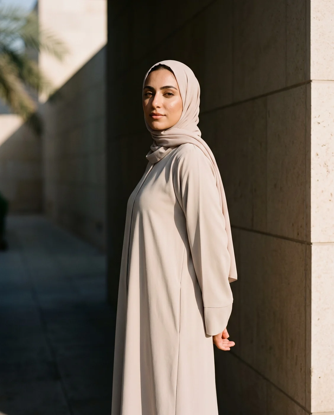 عارضة محجبة بعباية كريمية في ممر حجري